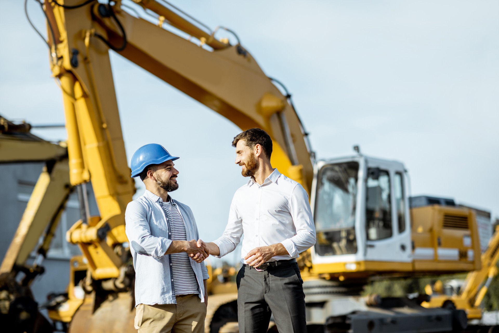 Builder with a sales consultant at the shop with heavy machinery